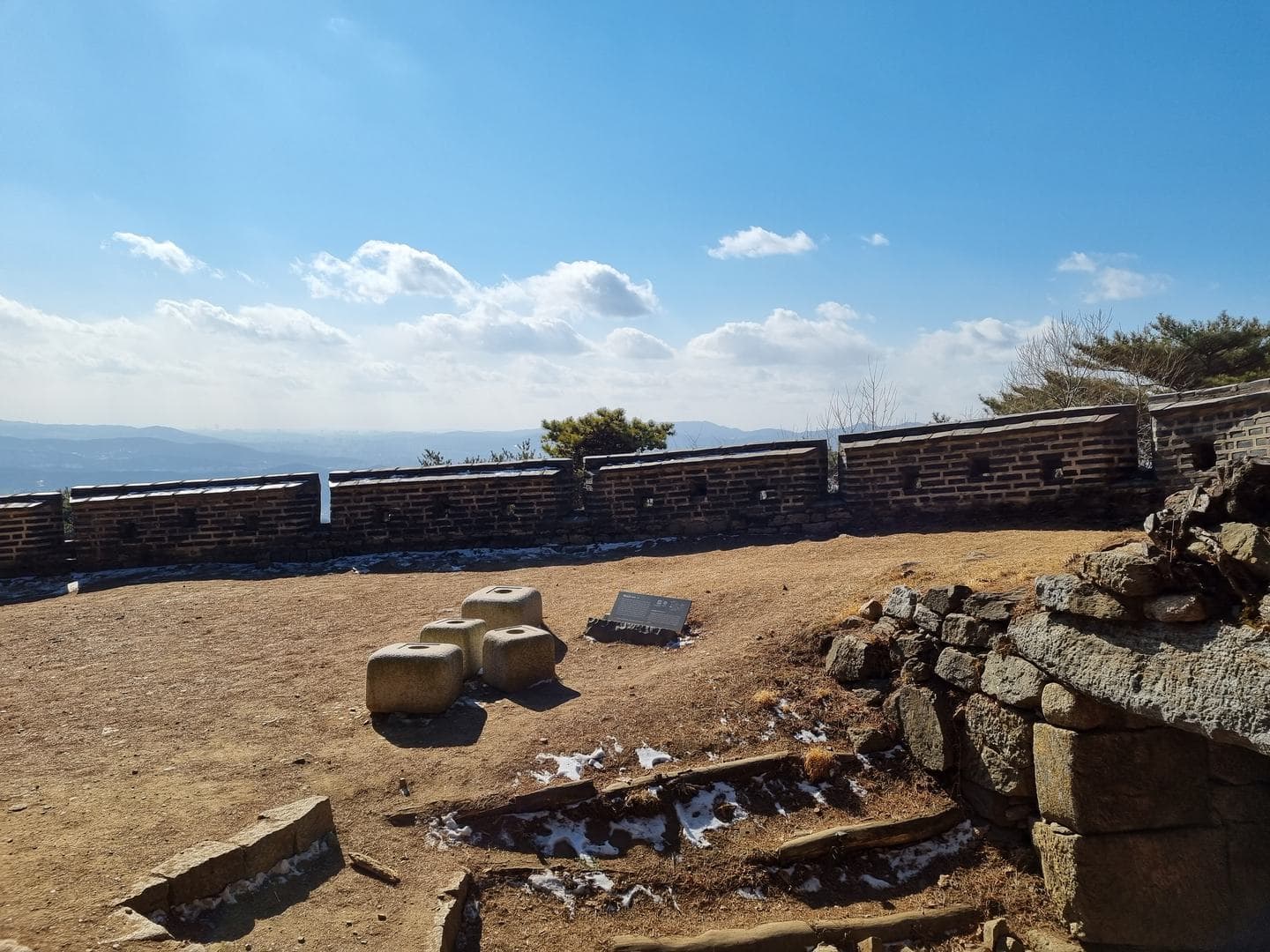Stone foundations and the fortress wall with views across the valley