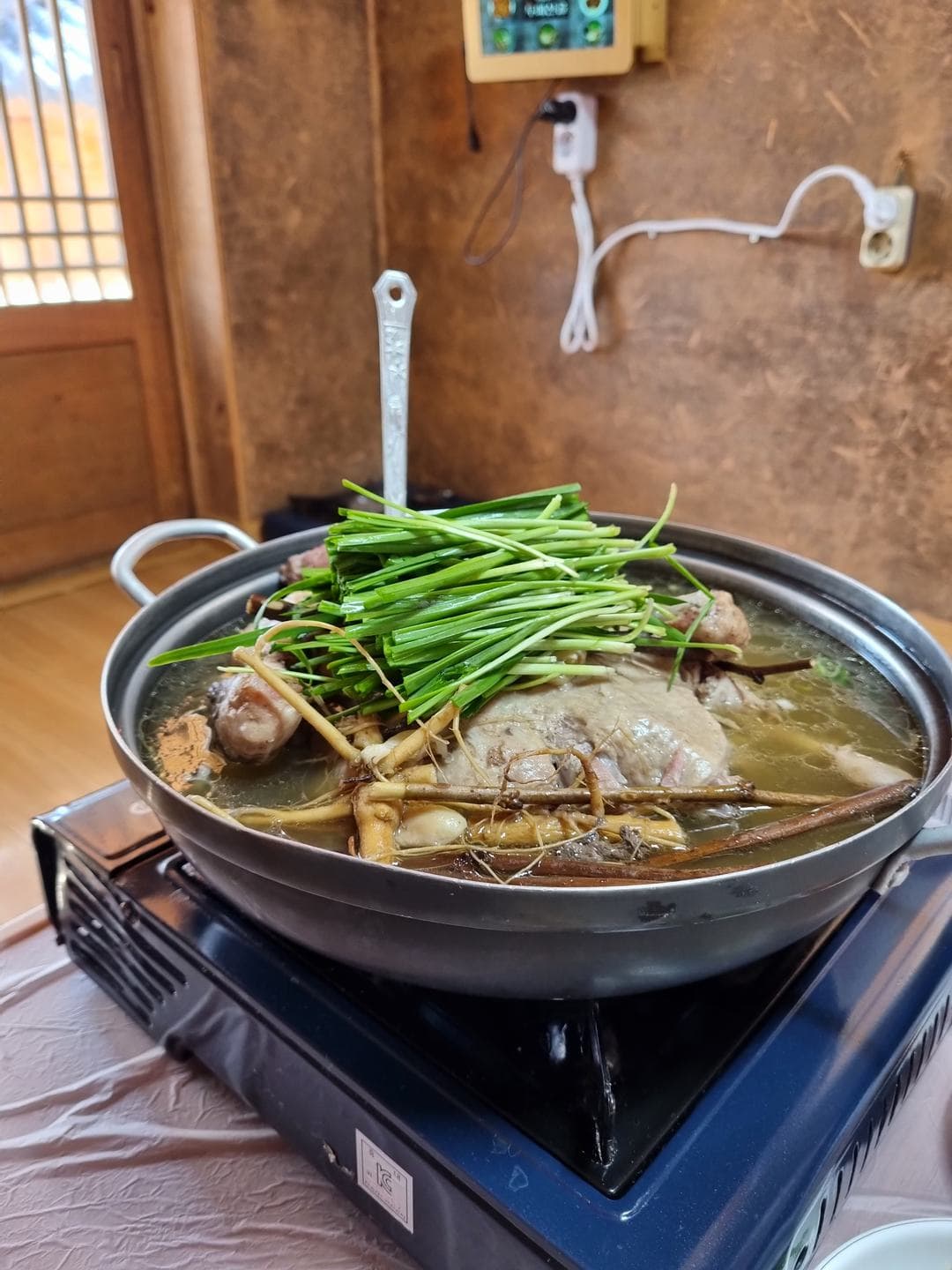 A pot of baeksuk with green onions on a portable burner