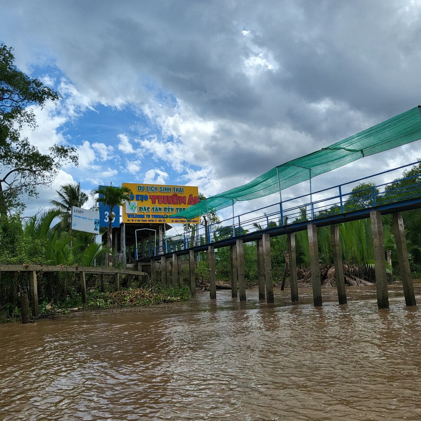 A wooden jetty and footbridge along a muddy canal