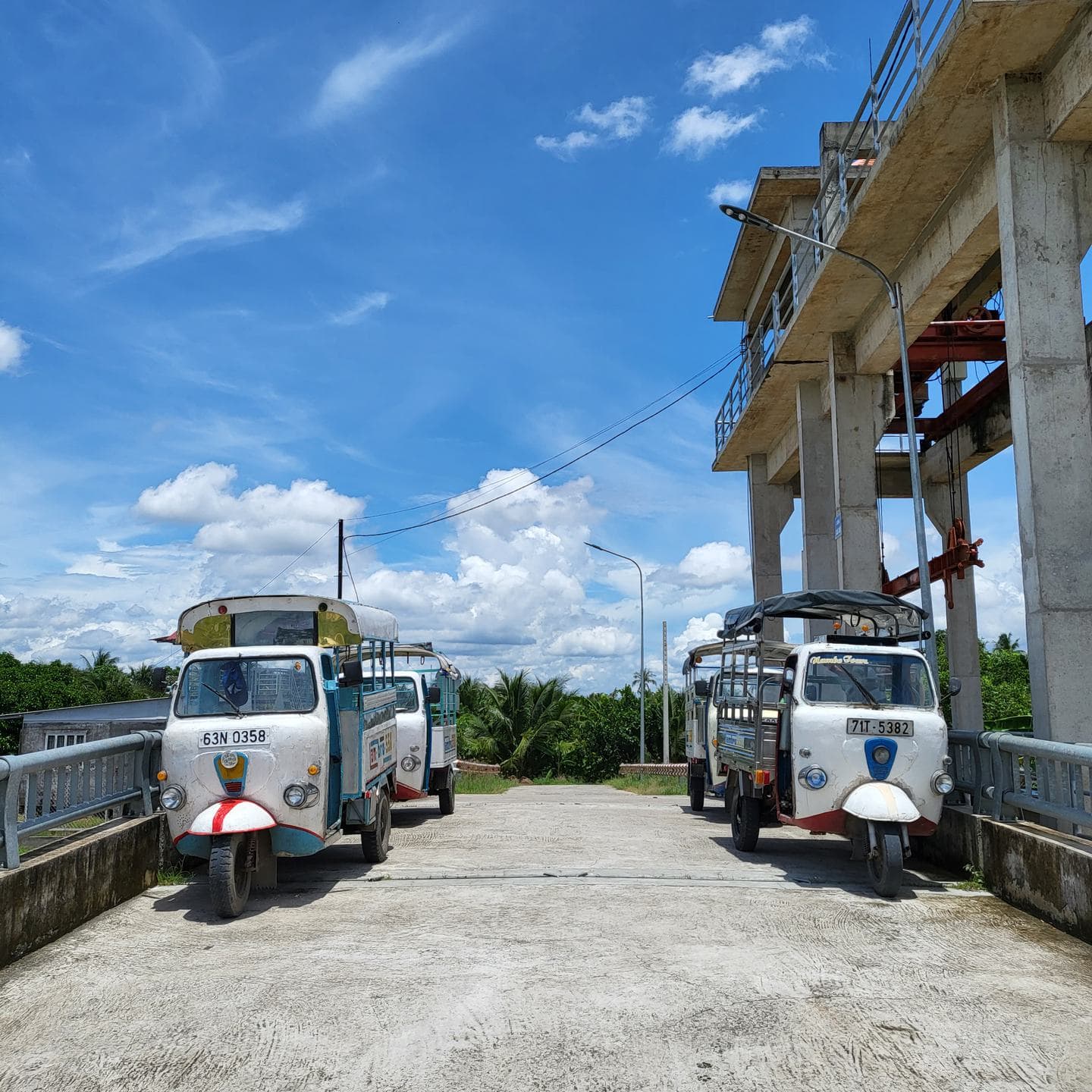 Two small passenger vehicles waiting on a concrete road