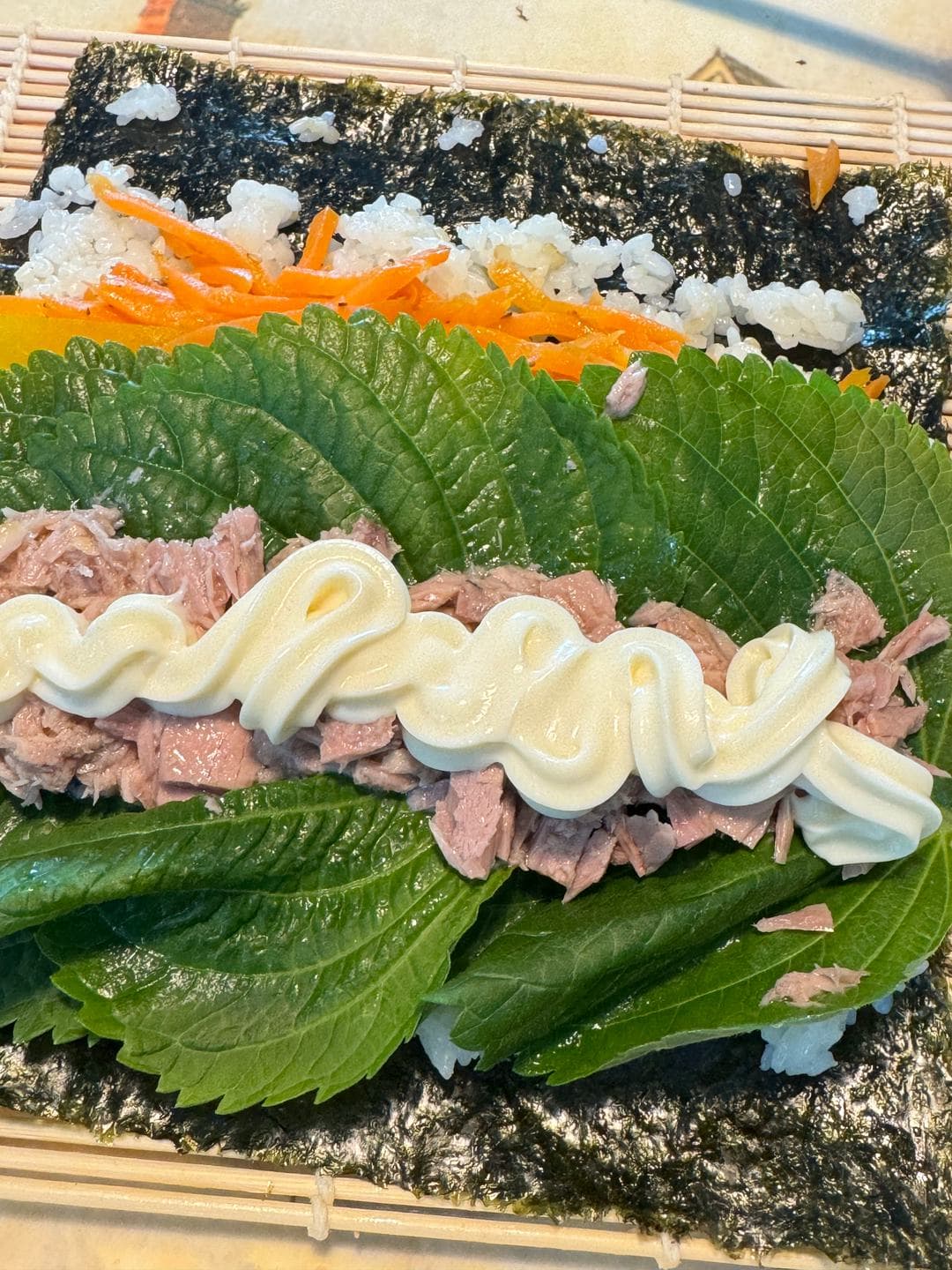 Mayonnaise piped over tuna and perilla leaves