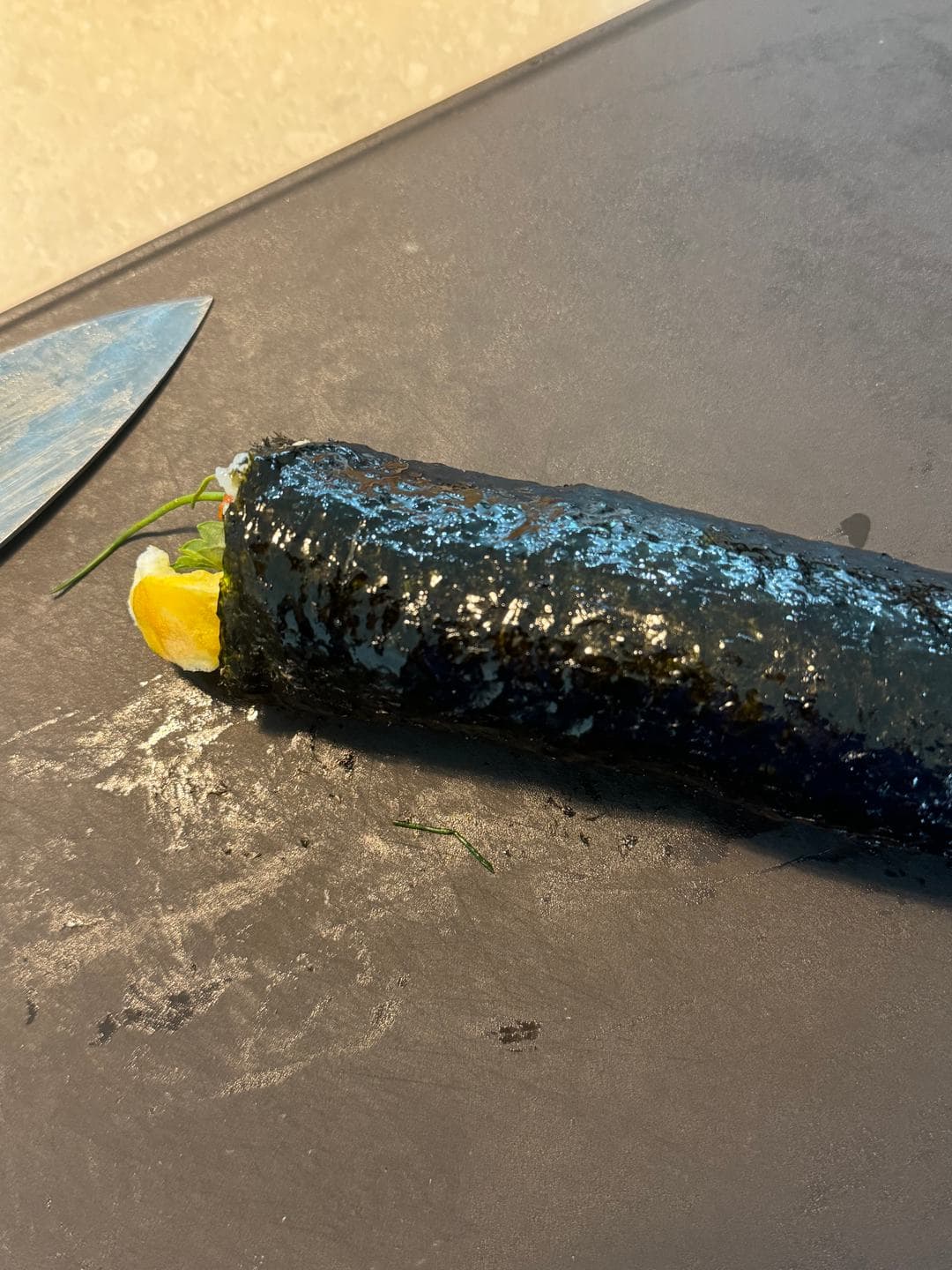 A finished gimbap roll on the counter, ready to slice