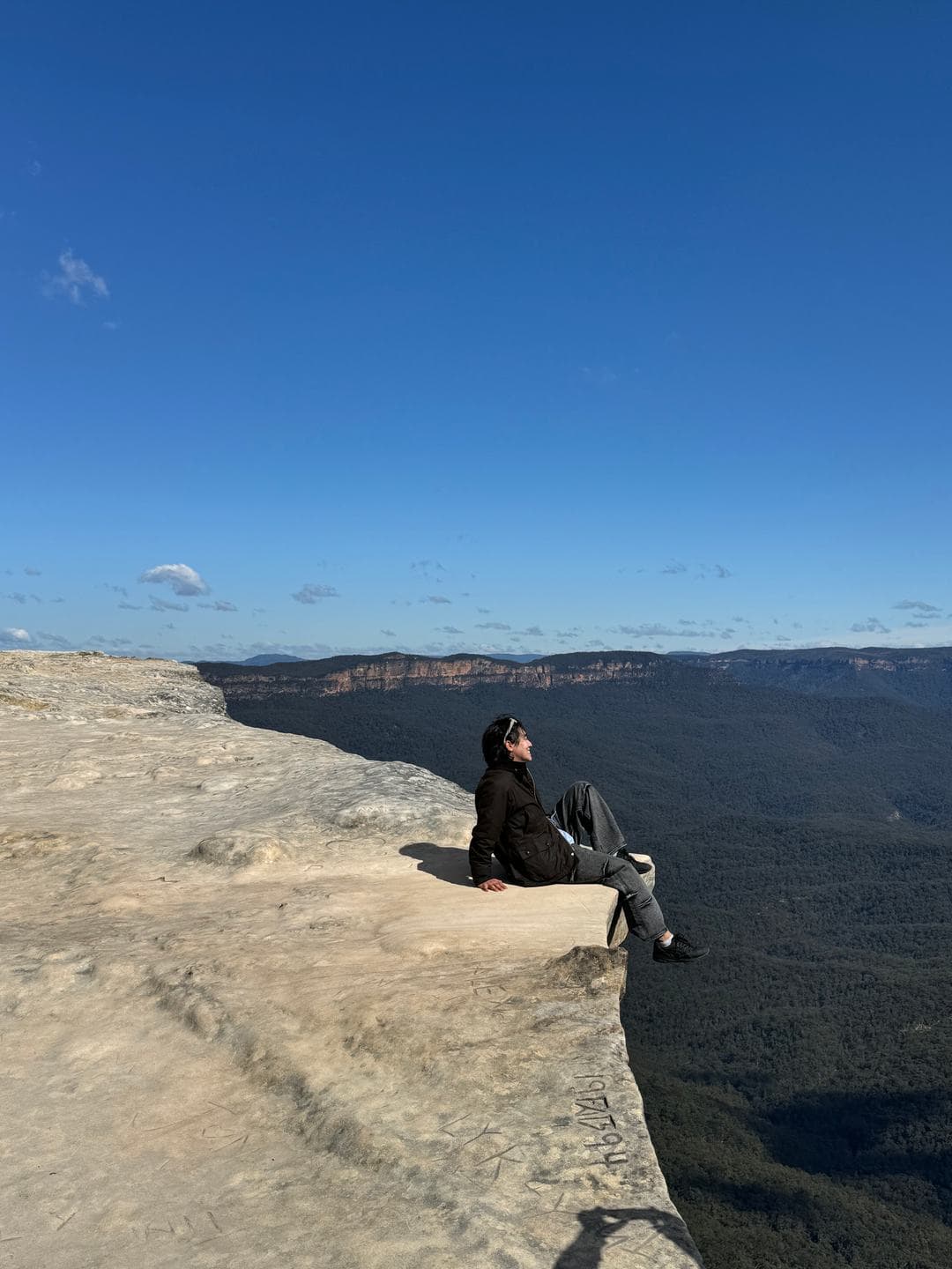 Sitting at the very edge of a flat rock ledge