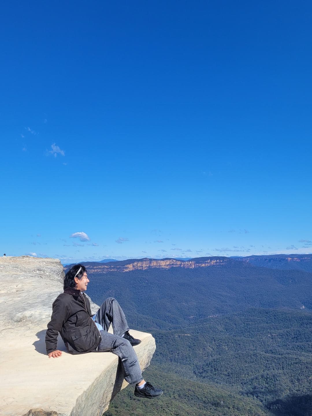 Legs stretched out on the sandstone ledge above the drop