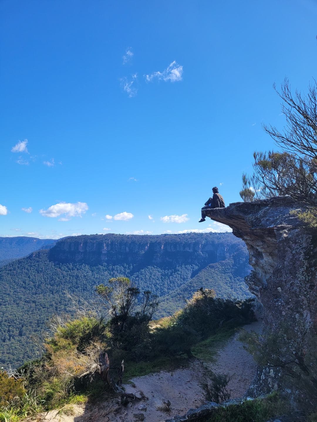A small figure on a rock outcrop over the valley