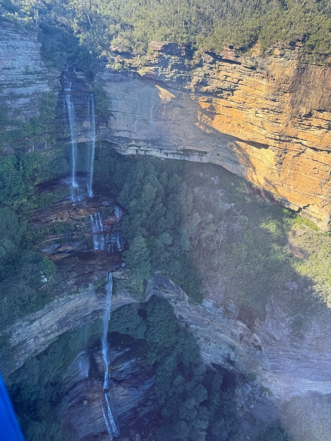 Katoomba Falls dropping in thin threads down an orange wall