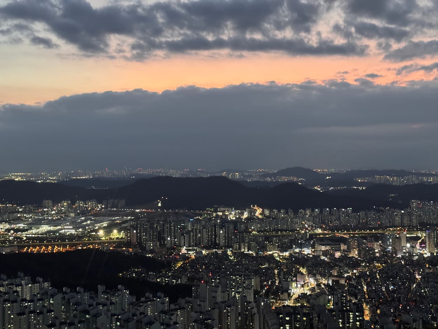 City lights spreading below the dark ridges after sunset