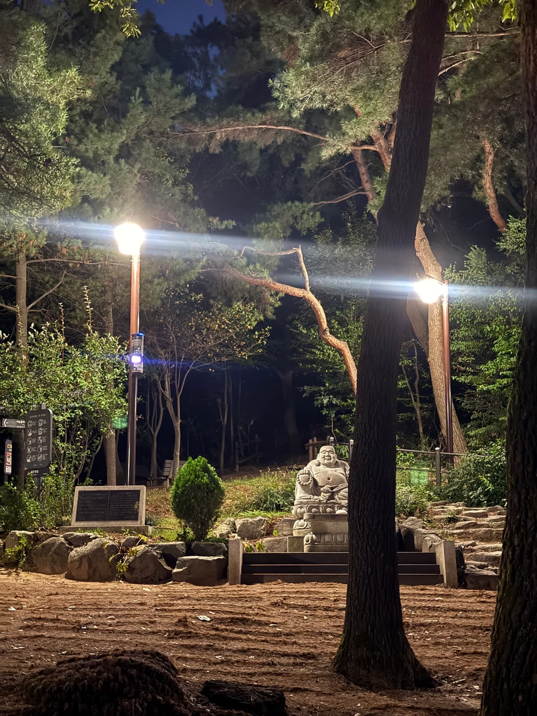 A stone statue and lamps in the temple yard at night