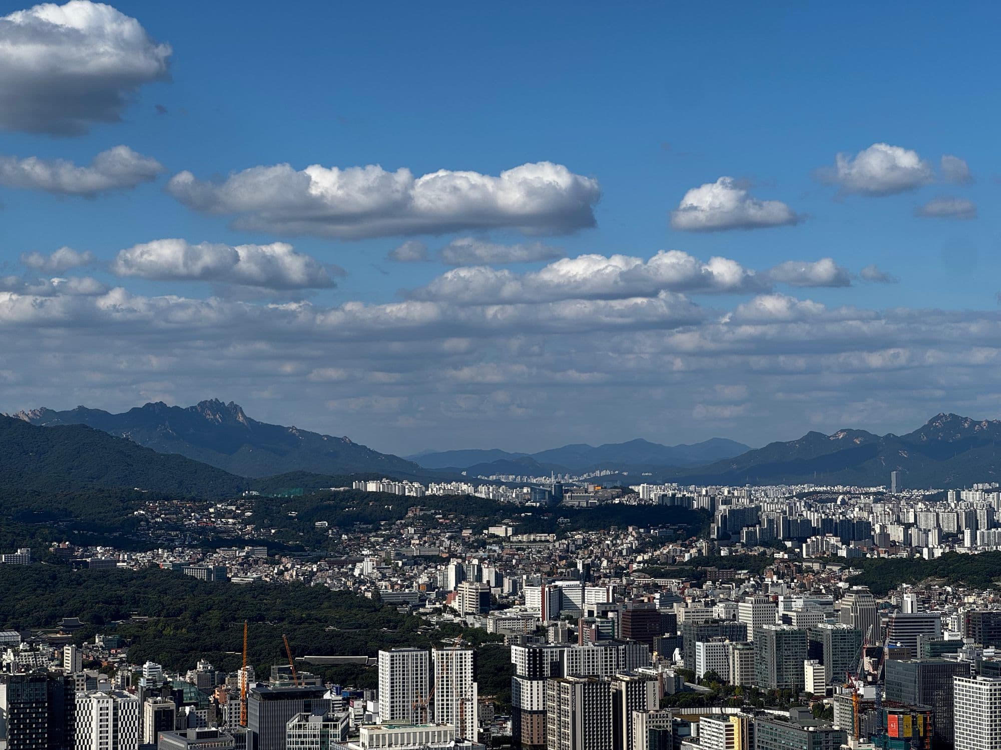 Seoul from Namsan: the city running to the horizon under bright clouds