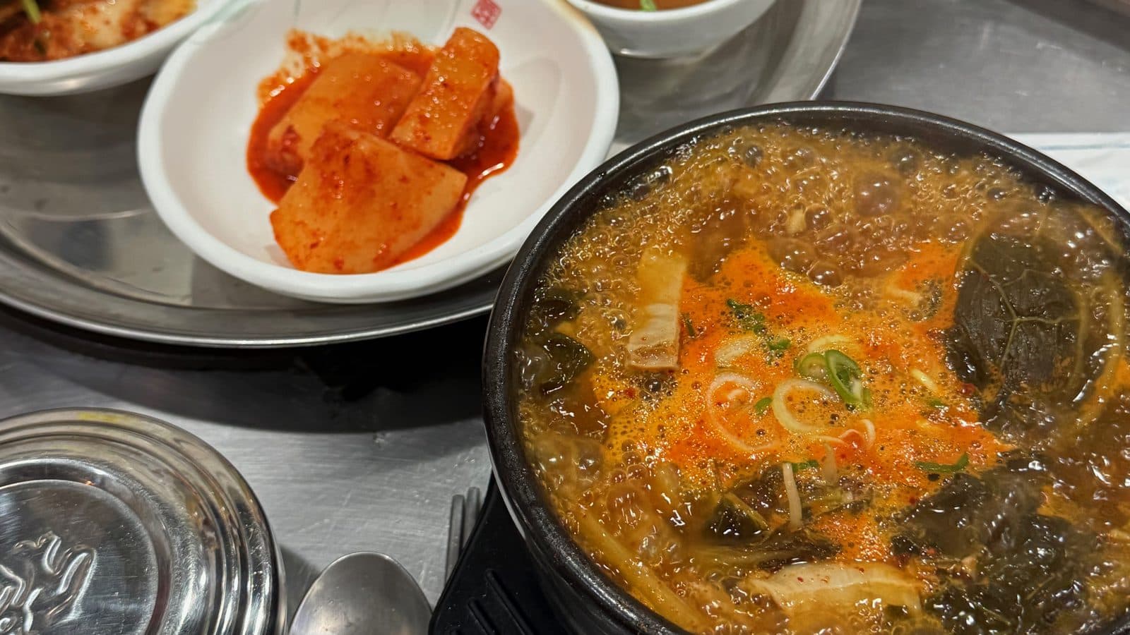 검은 뚝배기에 담긴 빨간 내장탕과 깍두기, 스테인리스 공깃밥이 놓인 왕곱창 테이블
