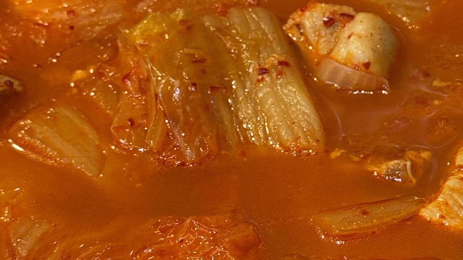 Primer plano de un kimchi jjigae rojo con kimchi de col y carne bien guisados