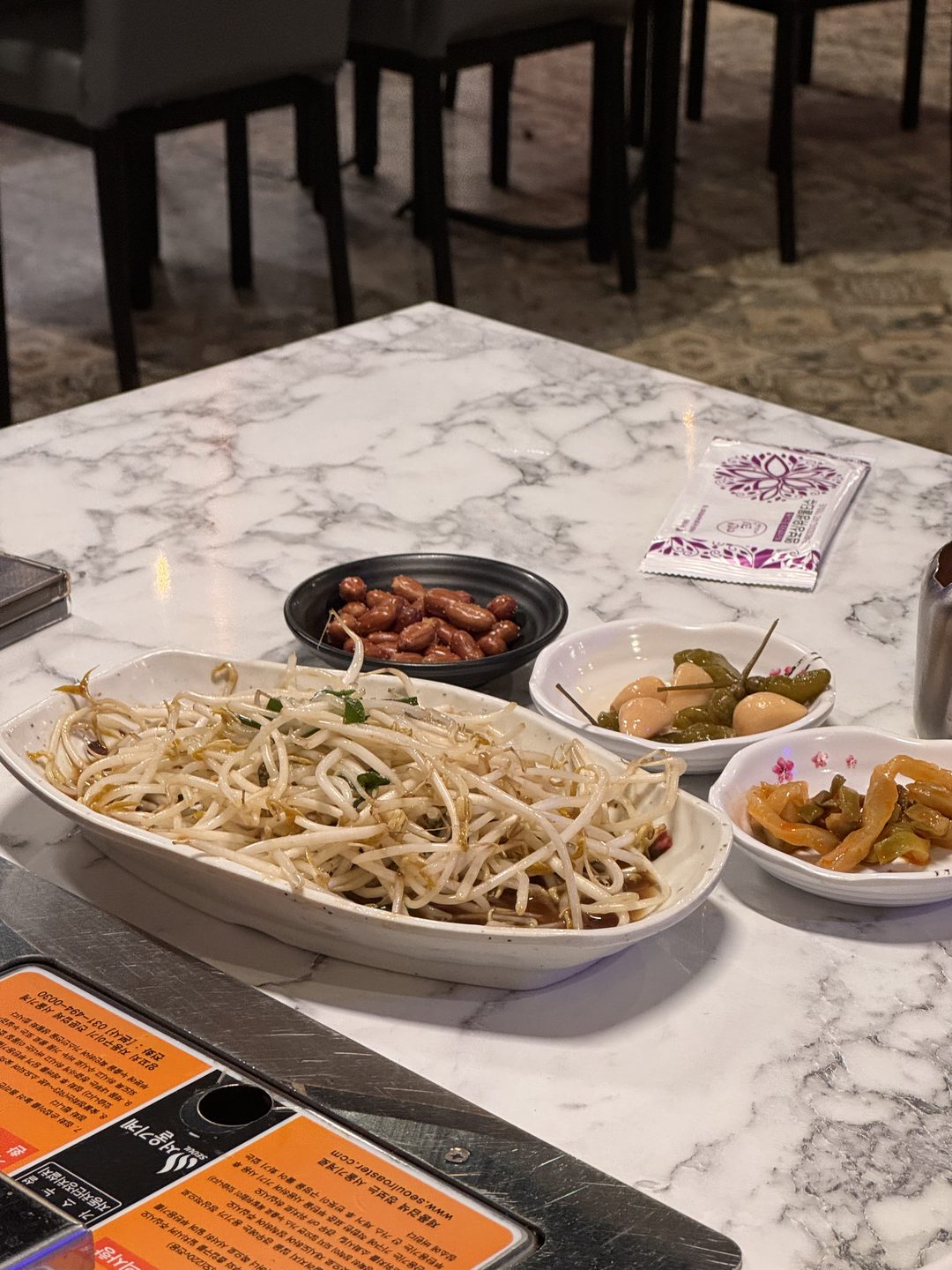 대리석 테이블 위의 숙주 무침, 볶은 땅콩, 절임 반찬