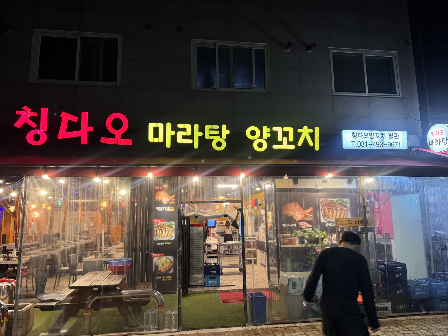 빨간 글씨로 칭다오, 노란 글씨로 마라탕 양꼬치라고 적힌 간판과 불이 켜진 가게 앞
