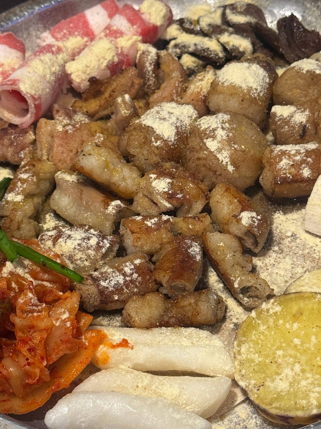 노릇하게 구워진 곱창과 대창, 부추와 김치를 가까이서 찍은 모습