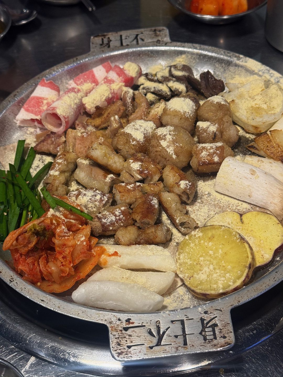 원형 철판 위에 곱창, 대창, 떡, 고구마, 부추, 김치가 빙 둘러 놓인 모듬곱창