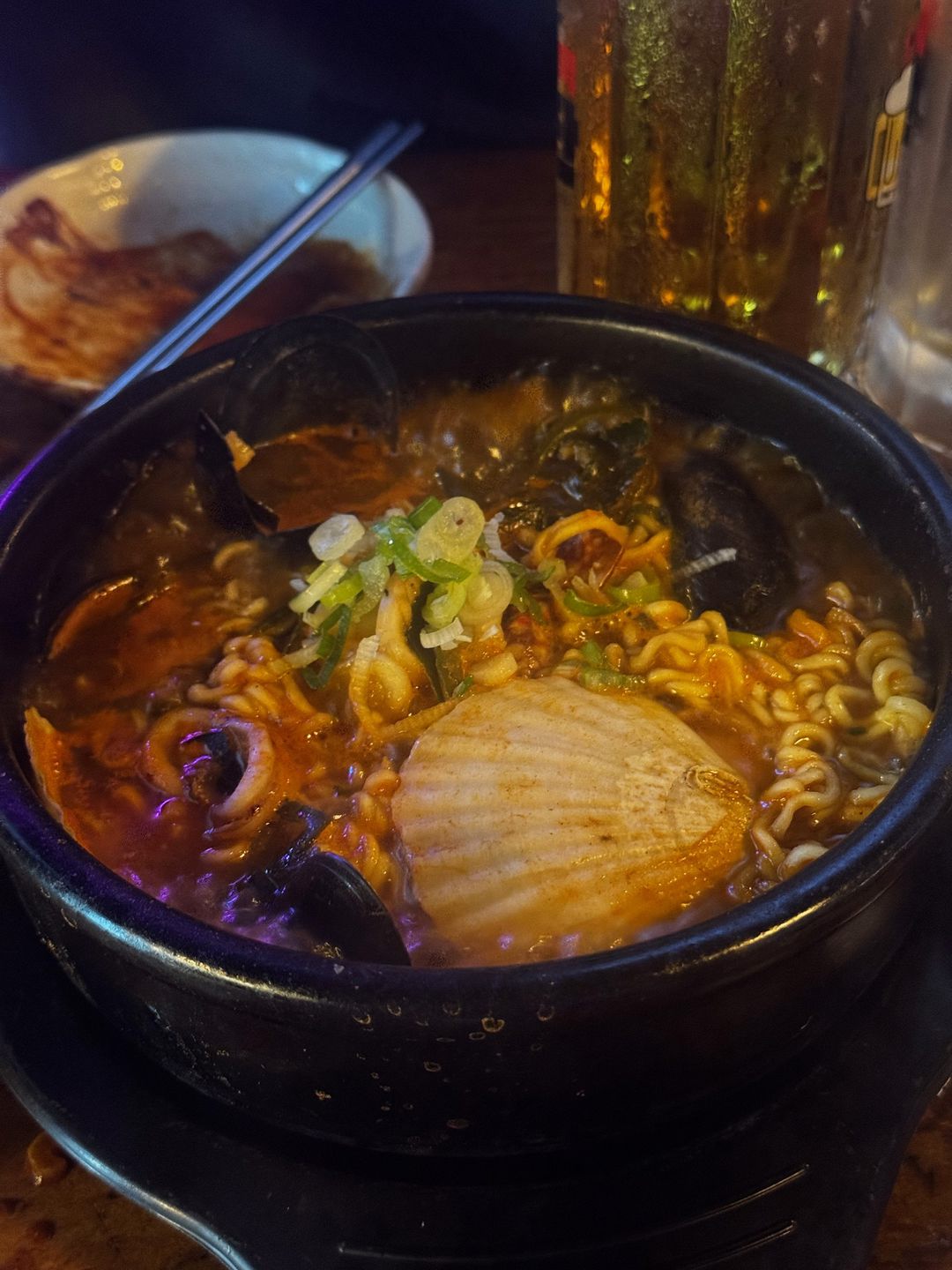 조개와 가리비, 파를 올린 빨간 라면이 담긴 검은 냄비
