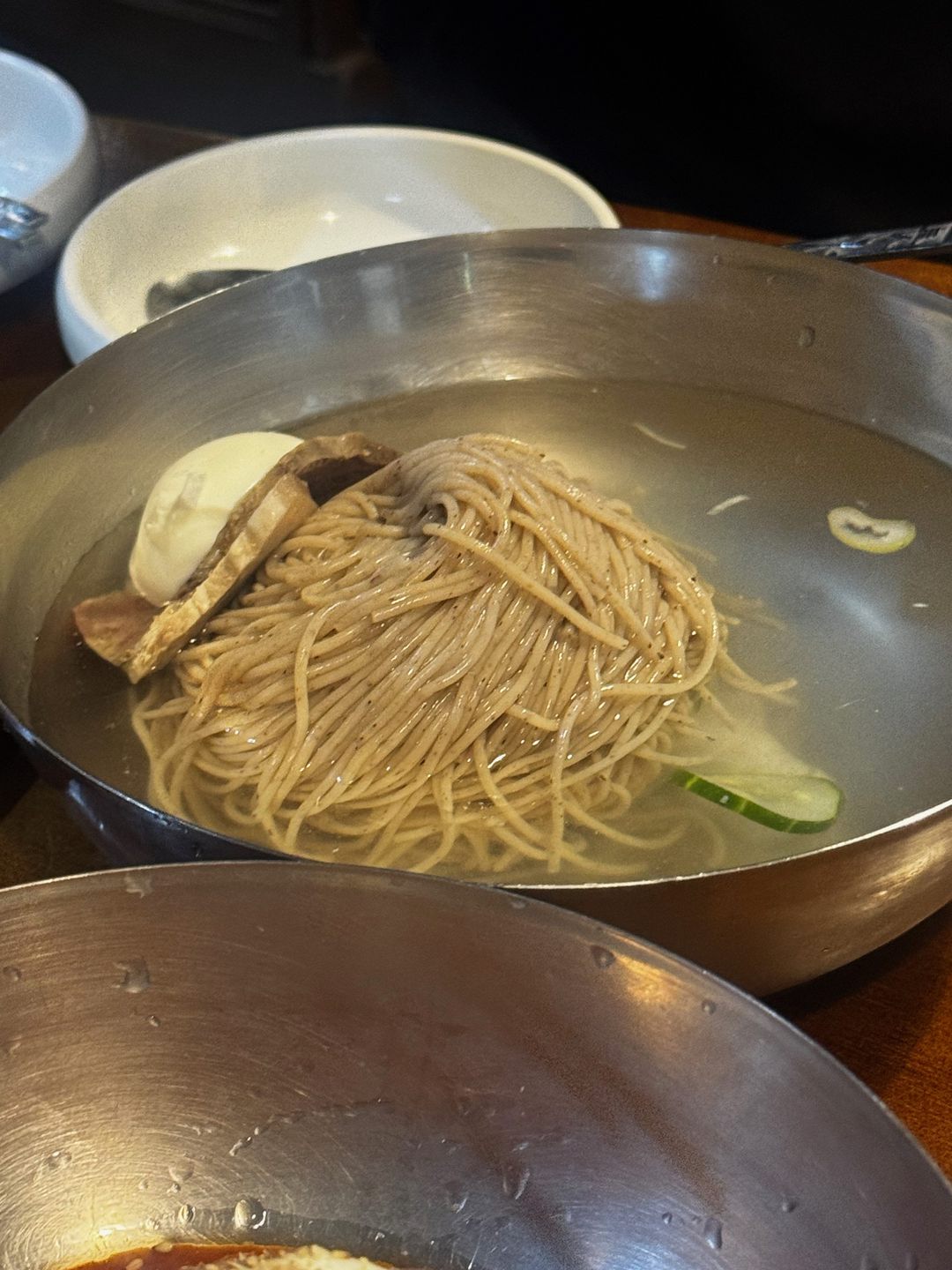 맑은 육수에 메밀면과 고기 편육, 반숙 계란, 오이를 올린 평양냉면