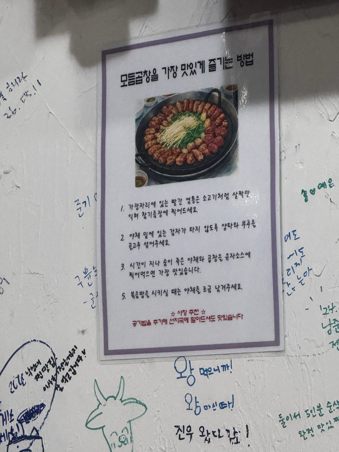 모듬곱창을 가장 맛있게 즐기는 방법이 적힌 포스터와 손님들의 벽 낙서
