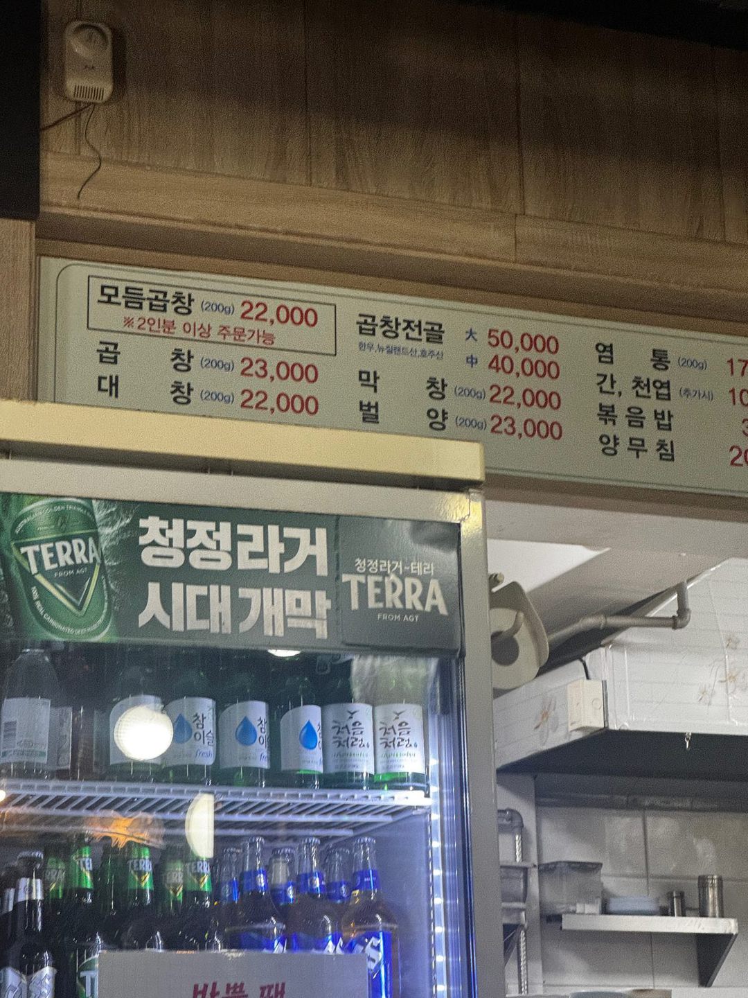 모듬곱창, 곱창전골, 곱창, 막창, 대창, 벌양 가격이 적힌 왕곱창 메뉴판과 맥주 냉장고