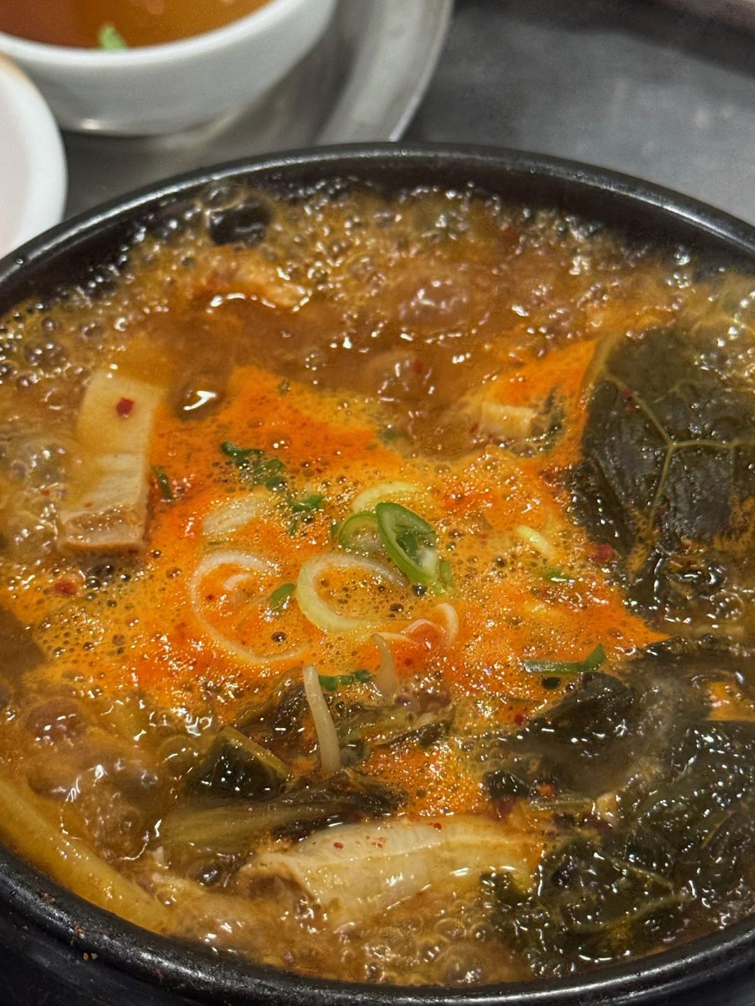 빨간 기름이 뜬 국물에 대파, 우거지, 당면이 들어간 뚝배기 내장탕