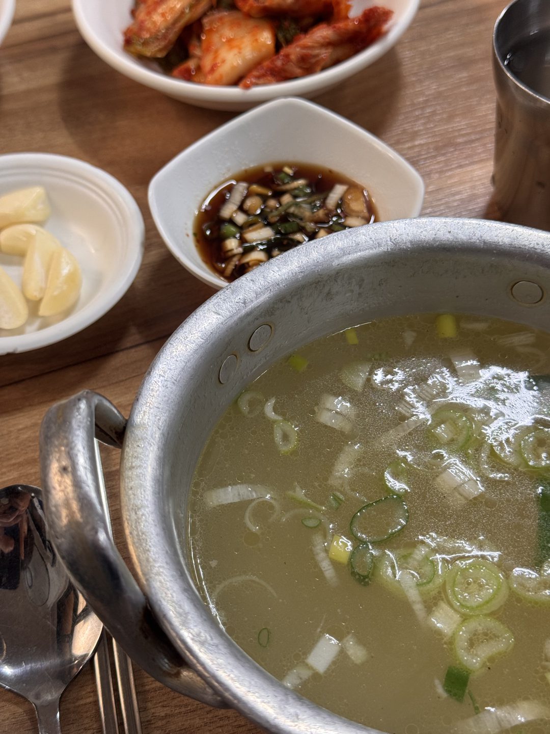송송 썬 대파가 뜬 맑은 닭곰탕 국물이 양은 냄비에 담겨 있다