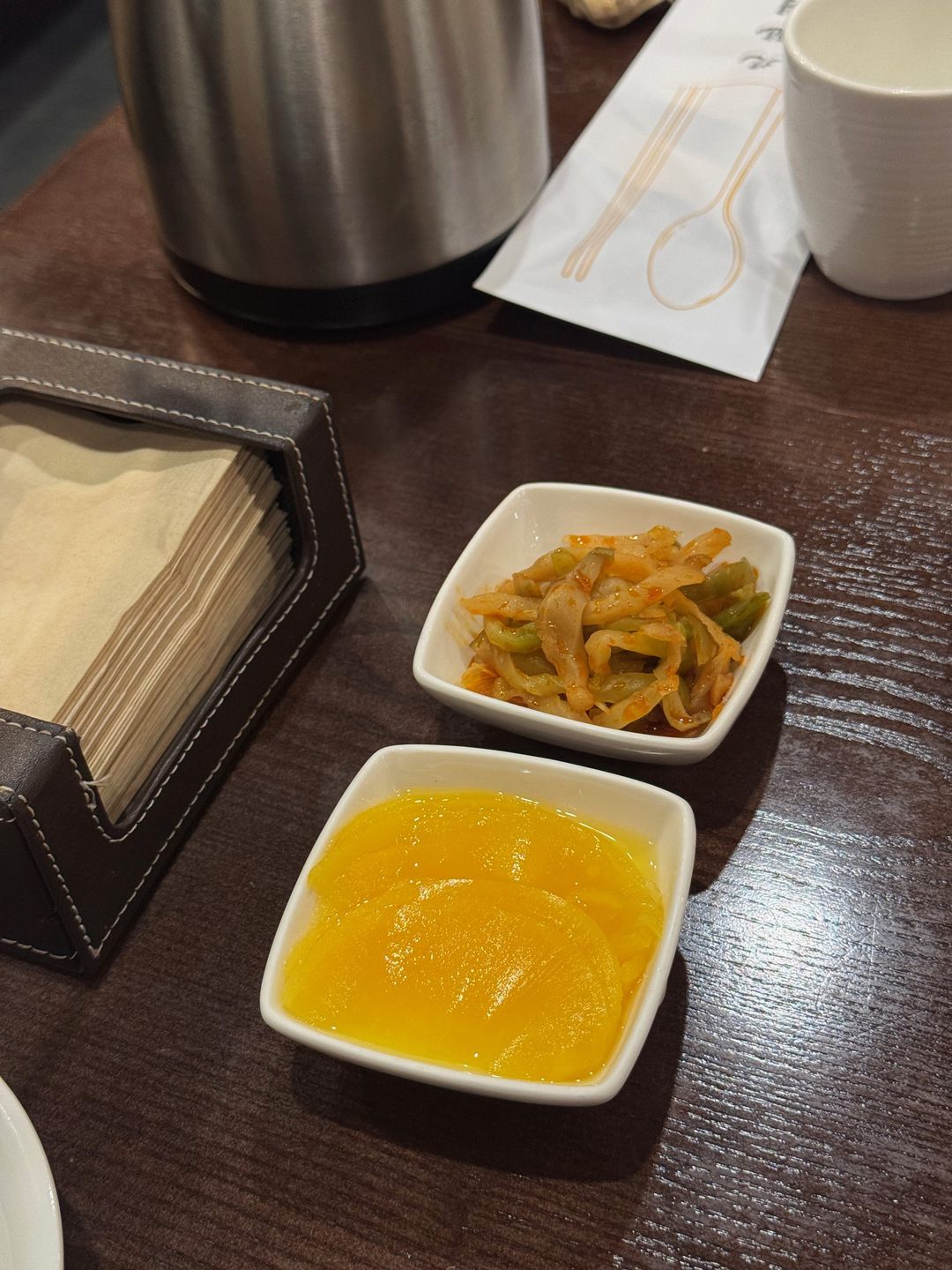테이블에 놓인 단무지와 자차이 기본 반찬, 냅킨 통과 물병