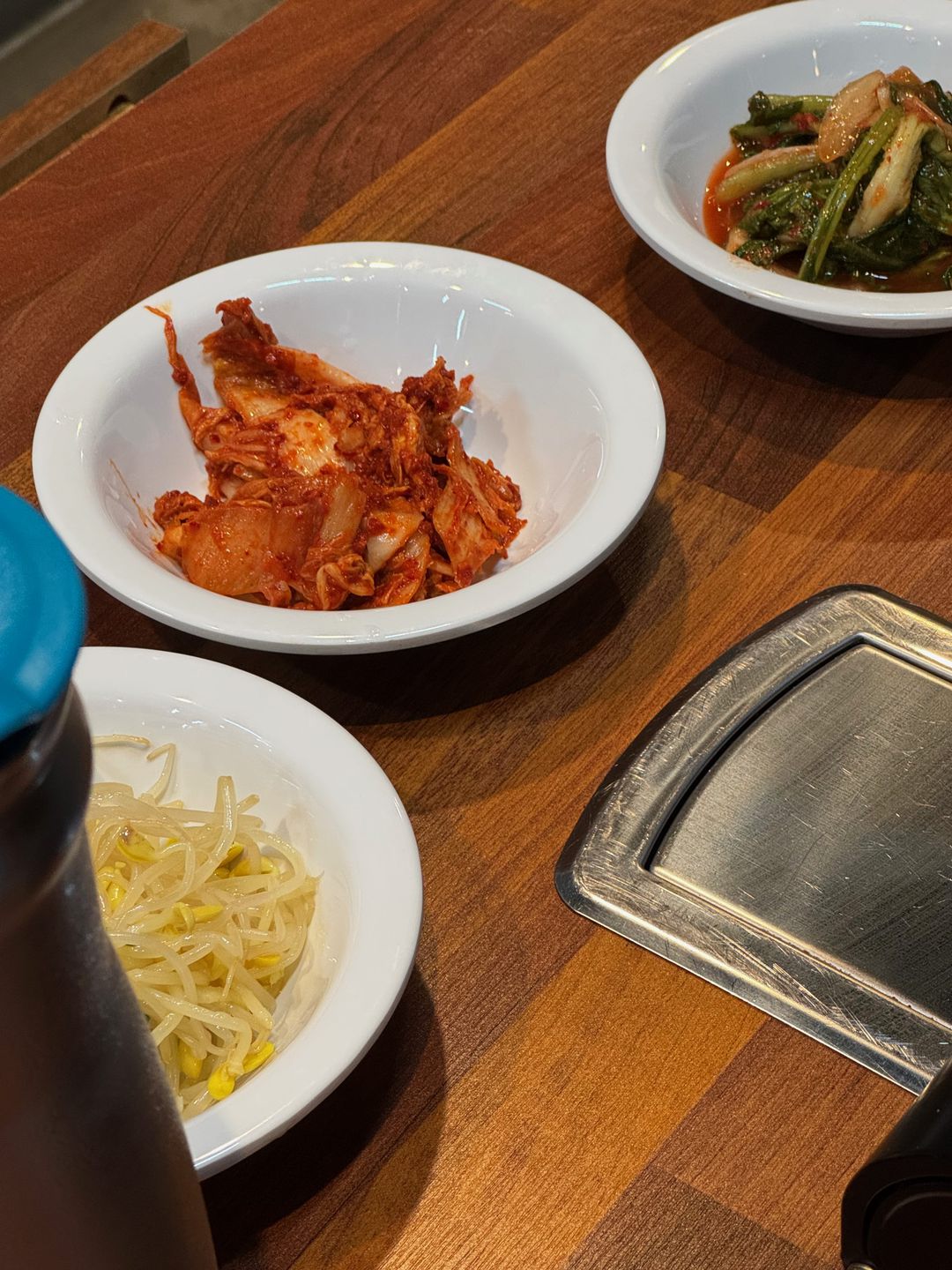 Platos de kimchi de col, namul y brotes de soja sobre una mesa de madera