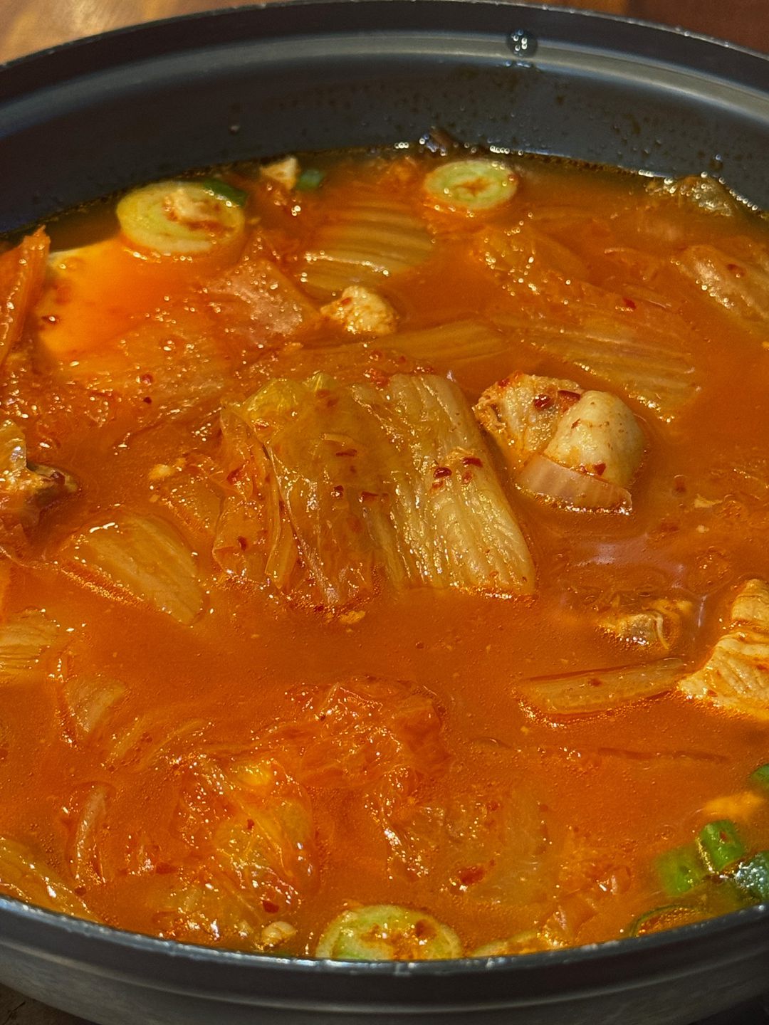 Kimchi jjigae rojo con kimchi de col y carne hirviendo en una olla